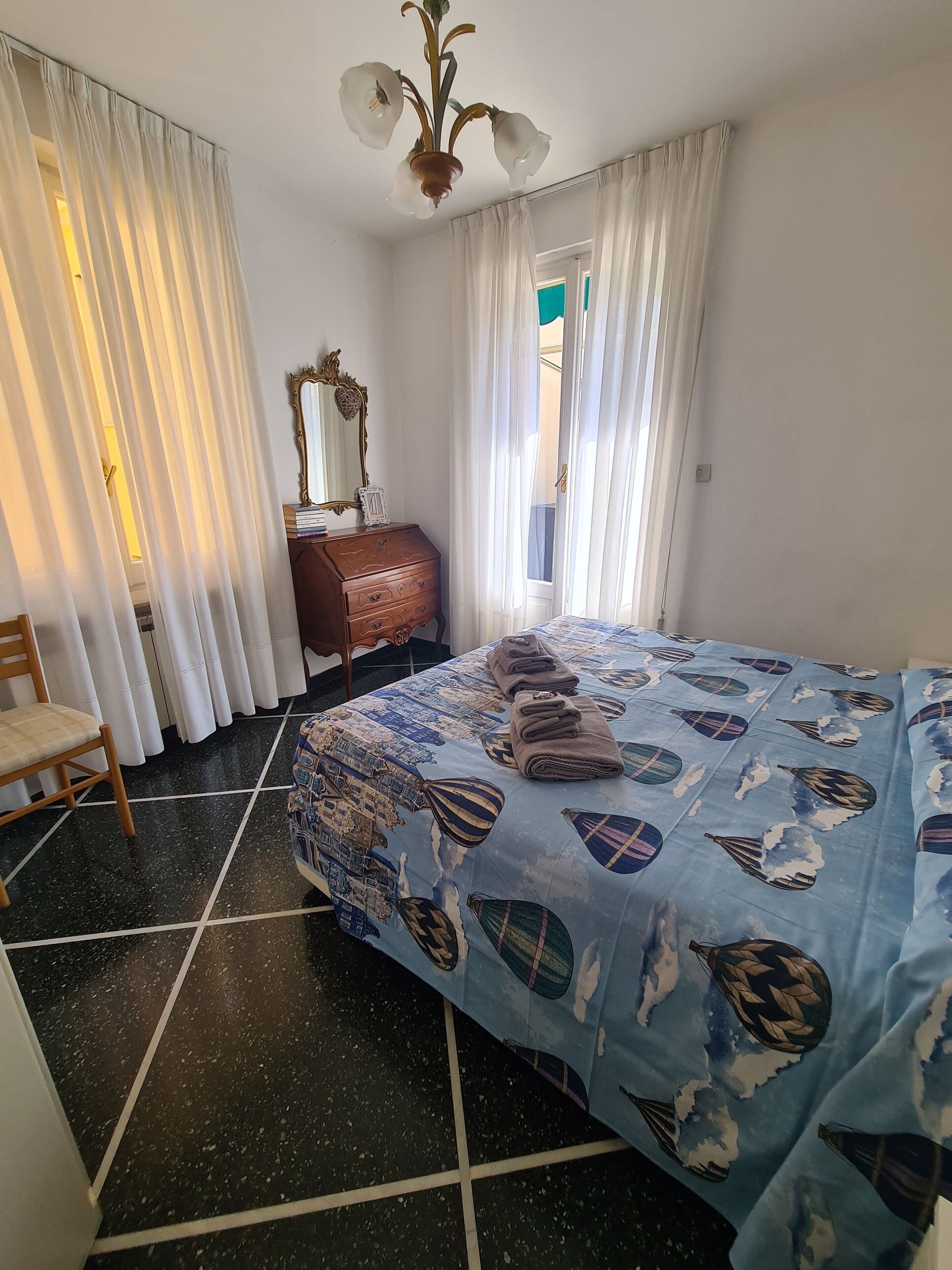 A bedroom with a bed, a dresser, a chair, and a window with curtains.