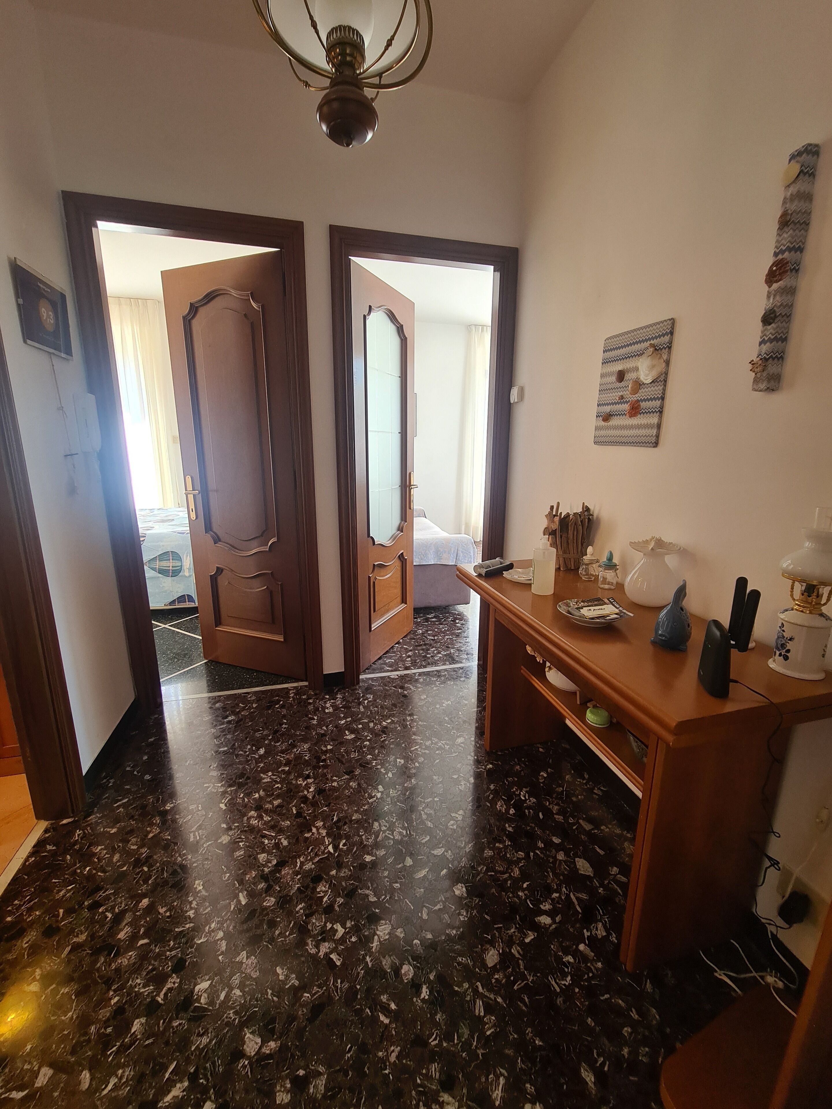 Une chambre d’hôtel avec un sol en marbre, des meubles en bois, un bureau avec une lampe et un lit recouvert d’une couette blanche.