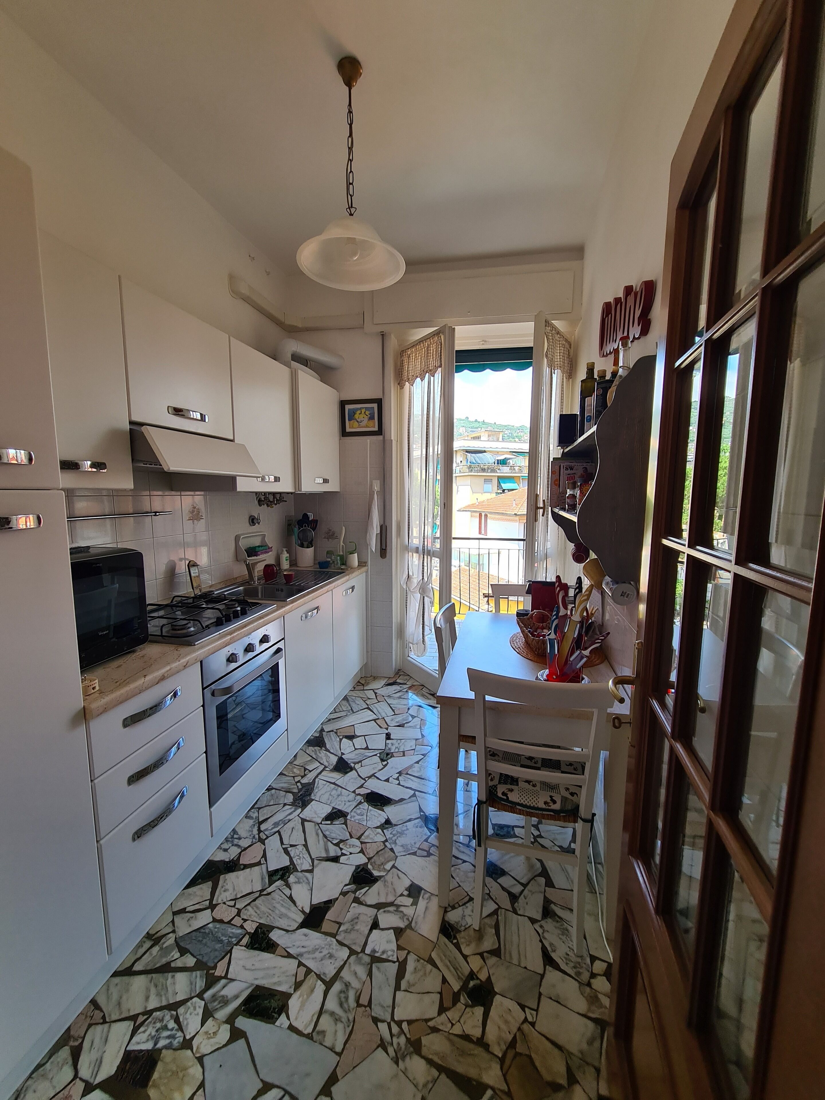 A kitchen with white cabinets, a gas stove, and a tiled floor.