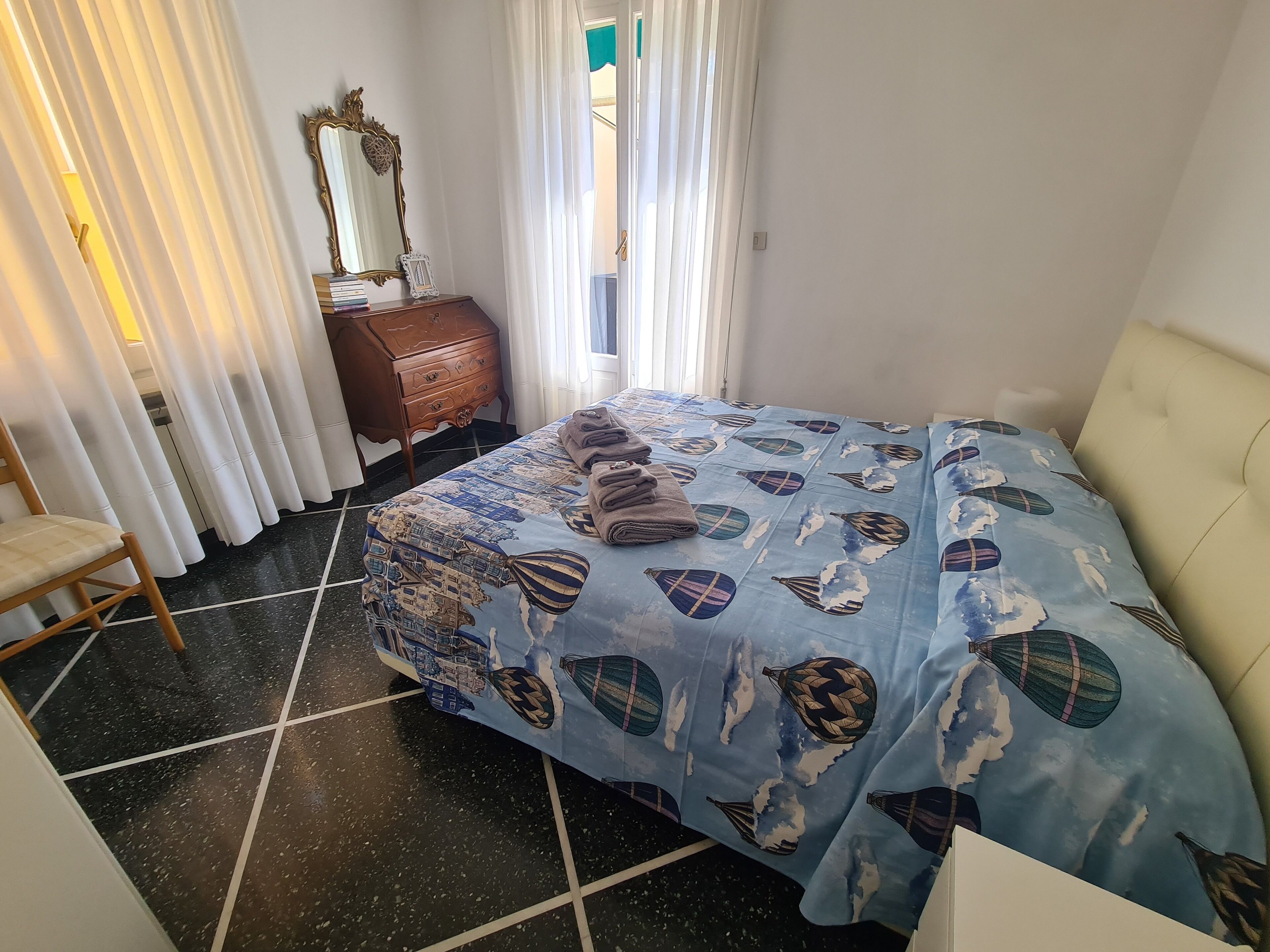 A bedroom with a bed, a dresser, a chair, and a window with curtains.