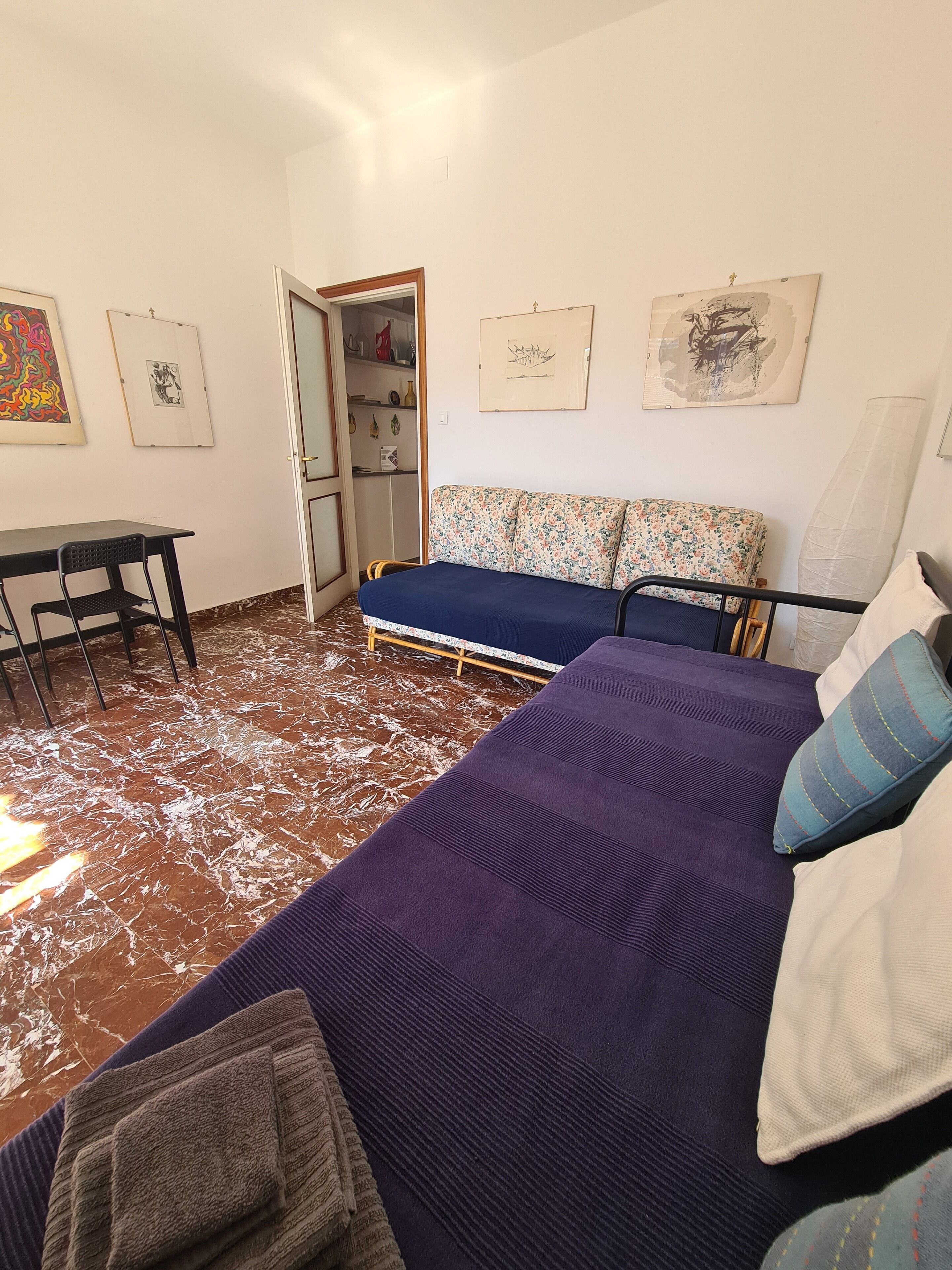 Un dormitorio con cama, escritorio y silla. En la pared hay cuadros enmarcados.
