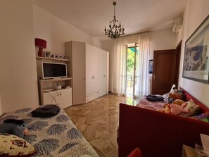 Ein Schlafzimmer mit einem Bett, einem Kleiderschrank, einem Fernseher und einem roten Sofa mit Stofftieren.