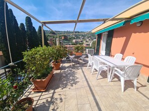 Ein Balkon mit Blumentöpfen, einem Tisch und Stühlen.