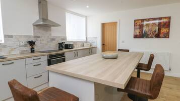 Una cocina moderna con una isla central, taburetes de madera y un cuadro grande en la pared.
