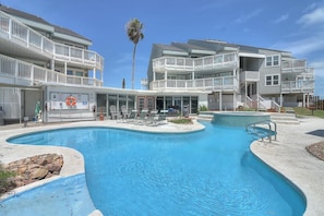 A pool area with a multi-level building, including balconies and a lifeguard stand.