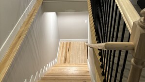 Un escalier en bois avec une rampe blanche et un mur de couleur claire.