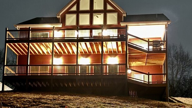 Une maison en bois à plusieurs étages, dotée de balcons et de grandes fenêtres, et caractérisée par une cheminée centrale imposante.