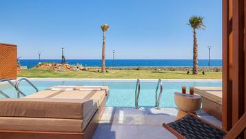 A poolside area with lounge chairs, a wooden deck, and a view of the ocean.