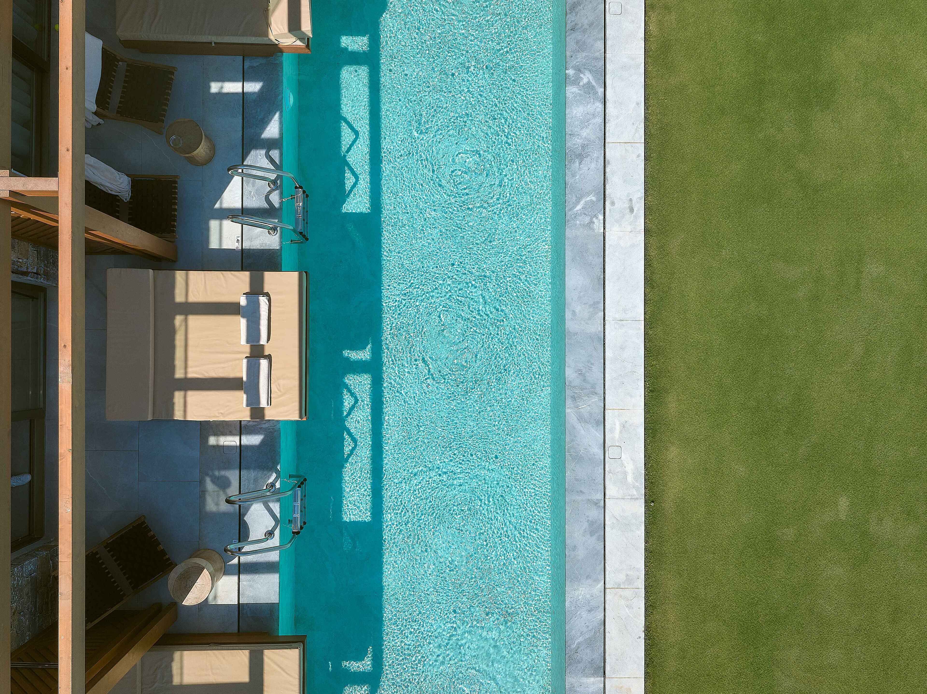 An aerial view of a swimming pool with lounge chairs and a grassy area.