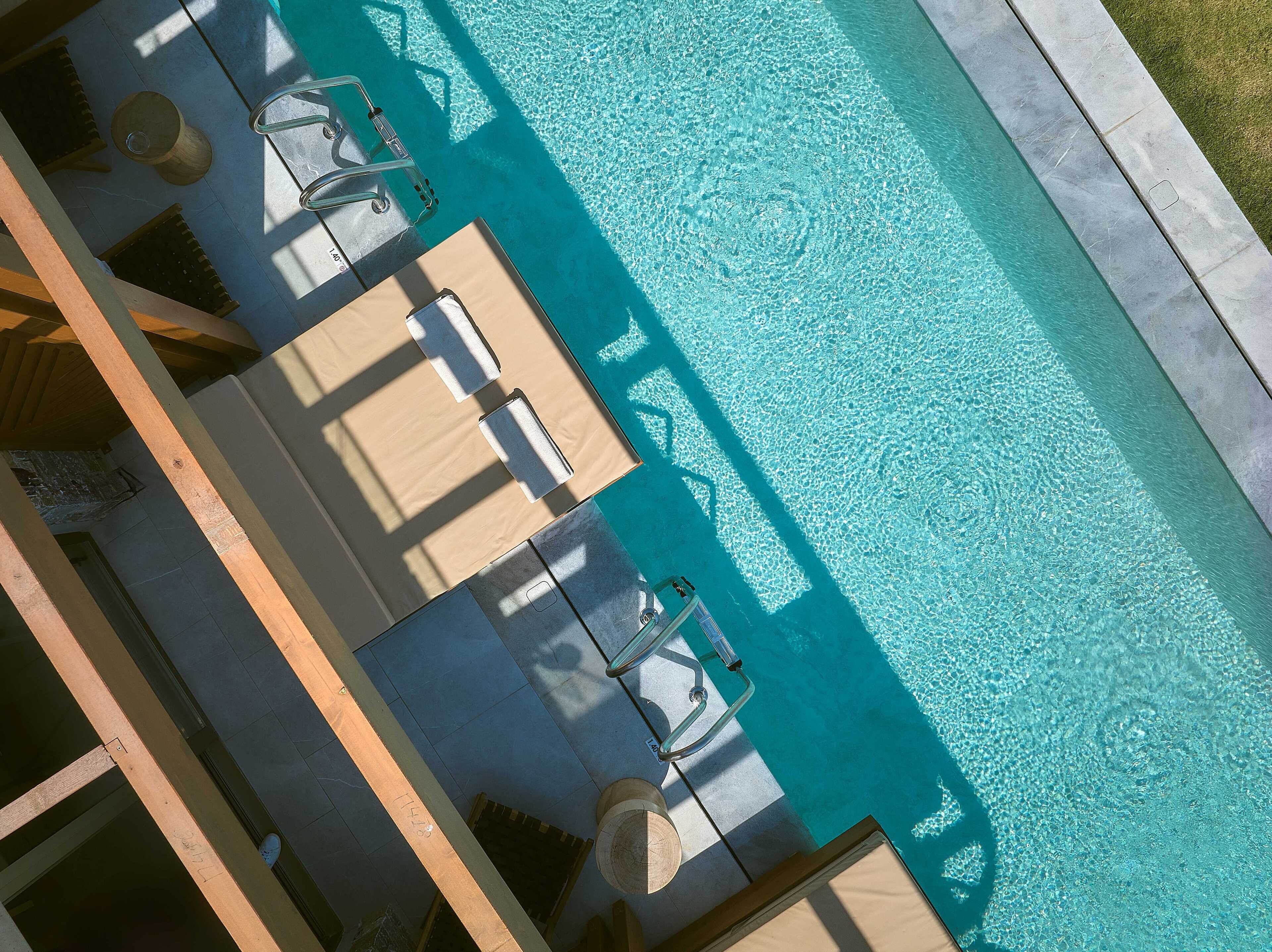 An aerial view of a swimming pool with lounge chairs and a wooden deck.