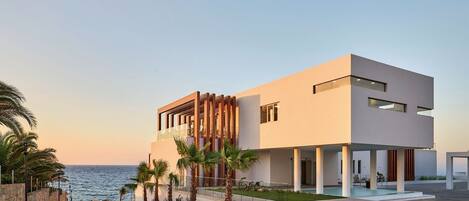 A modern two-story building with a pool, located near the sea.