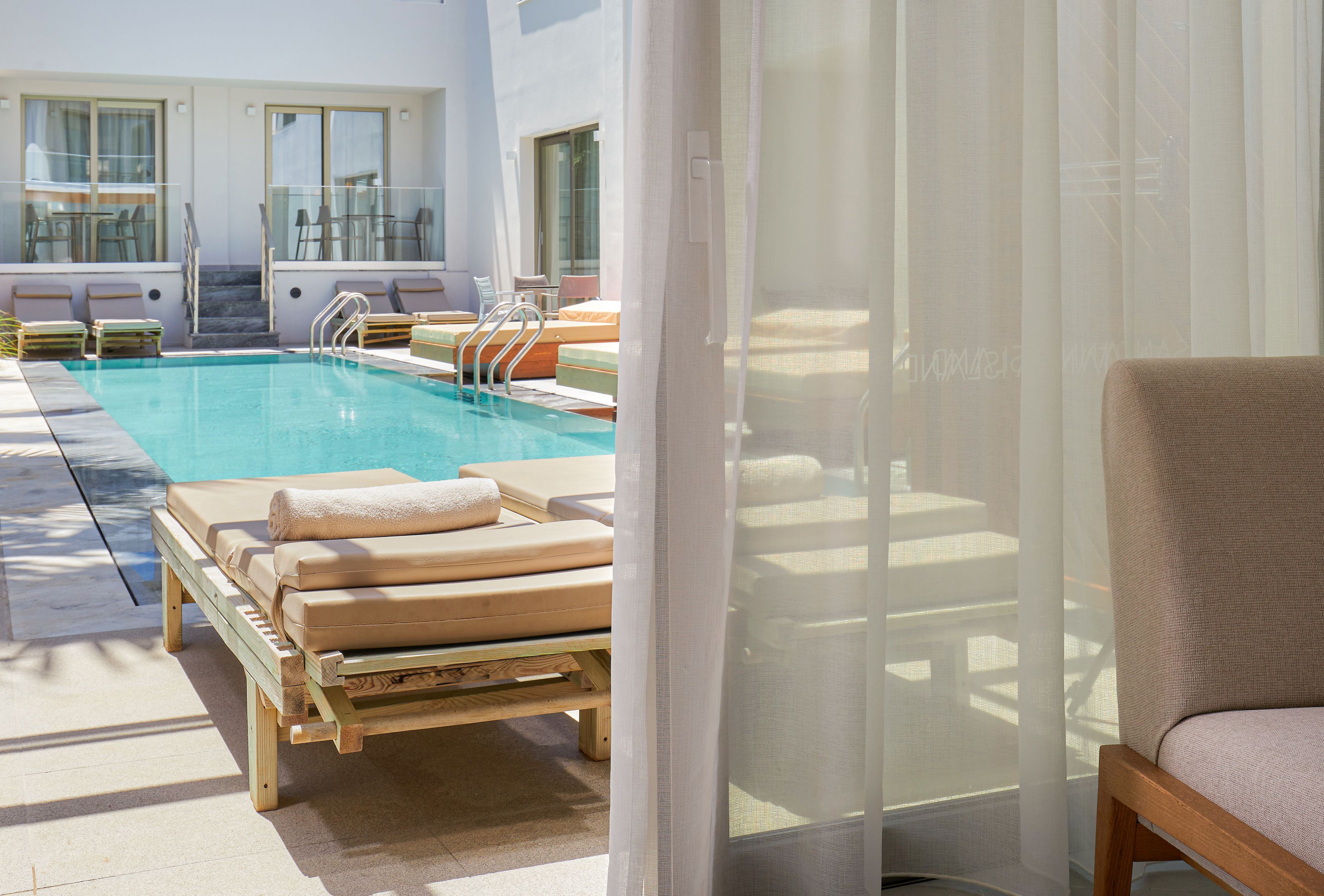 A pool area with lounge chairs and a staircase leading to an upper level.