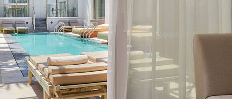 A pool area with lounge chairs and a staircase leading to an upper level.