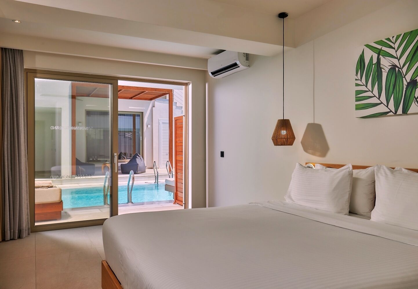A hotel room with a large bed, a view of a pool, and a sliding glass door leading to an outdoor seating area.