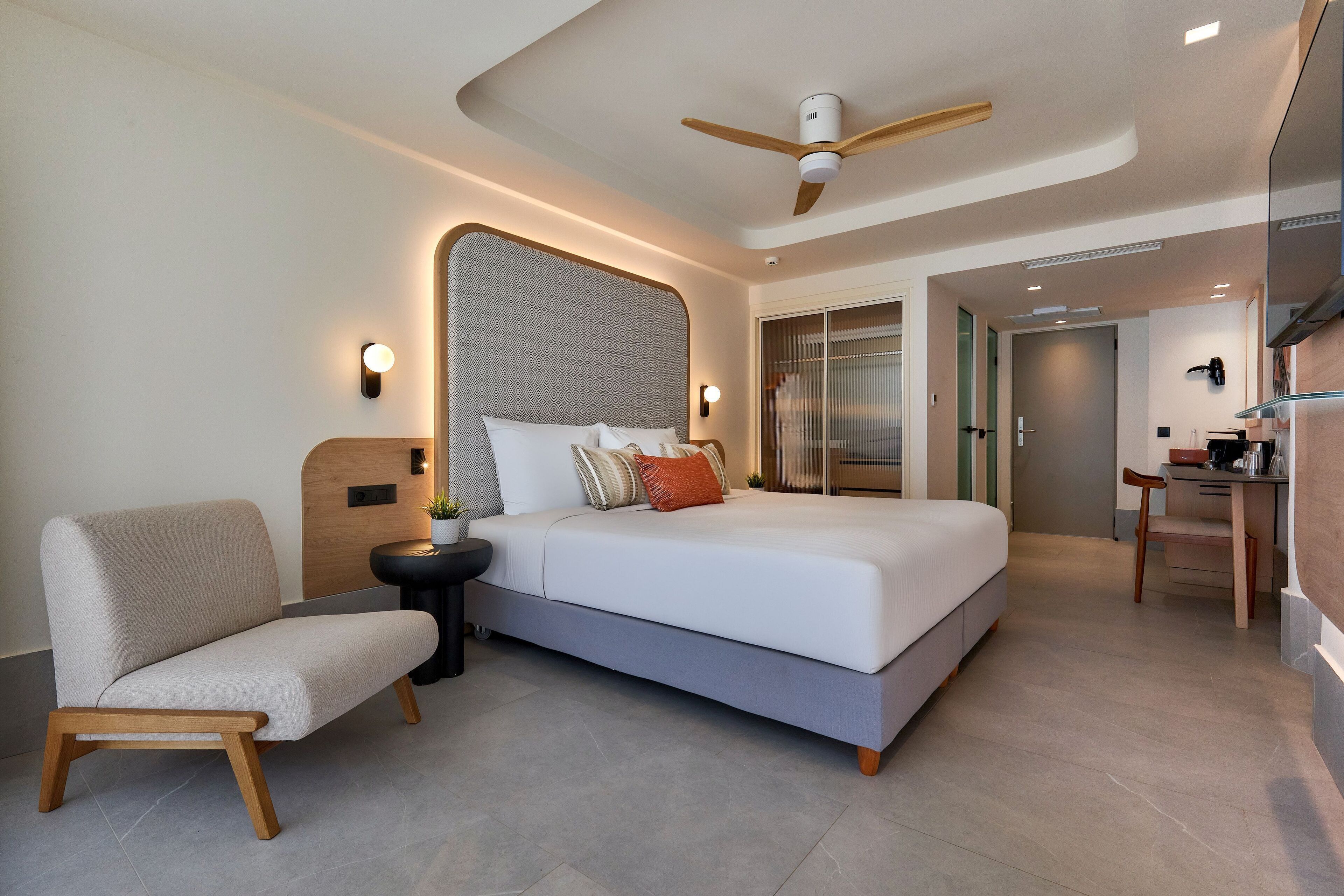 A modern bedroom with a bed, a chair, a desk, and a ceiling fan.