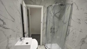 Une salle de bain moderne avec un meuble-lavabo en marbre, une cabine de douche en verre et des toilettes.