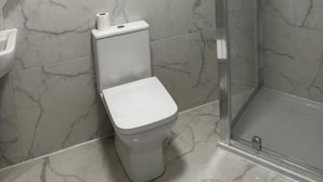 A bathroom with a toilet, a sink, and a glass-enclosed shower. - Cheetham Hill Guest House (Manchester)