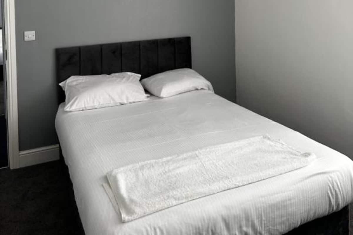 A bedroom with a bed, grey walls, and a dark headboard.