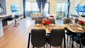 Habitació d'hotel moderna amb zona de menjador, saló i una finestra gran amb cortines.