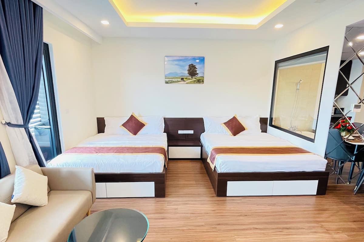 Una habitación de hotel con dos camas, un sofá, una mesita y un espejo grande.