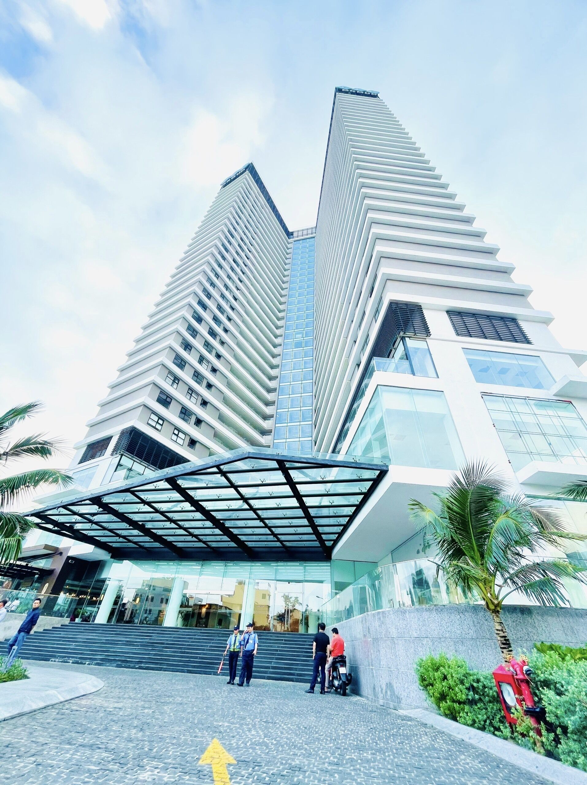 A modern building with a unique angular design, featuring a glass facade and a covered entrance area.