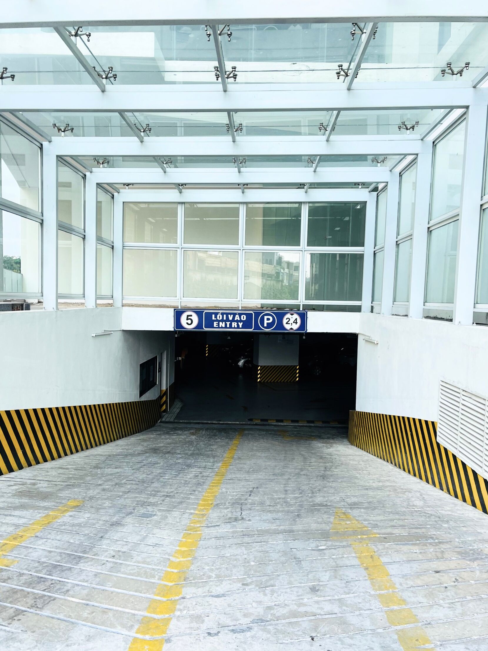 A parking garage entrance with clear signage for parking and entry, and a ramp leading down.