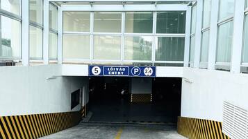 A parking garage entrance with clear signage for parking and entry, and a ramp leading down.