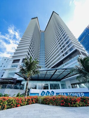 A modern high-rise building with a glass facade, a prominent entrance with a 'Welcome' sign, and a nameplate 'SEA TOWER'. - FLC Sea Tower Ocean View Quy Nhon (Quy Nhon Nam)