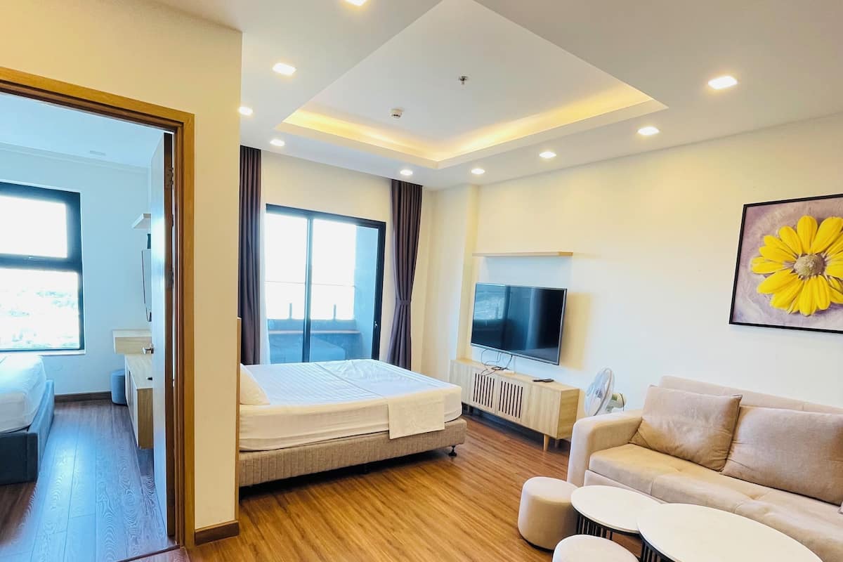 Una habitación de hotel moderna con una cama, televisor, sofá y zona de comedor.
