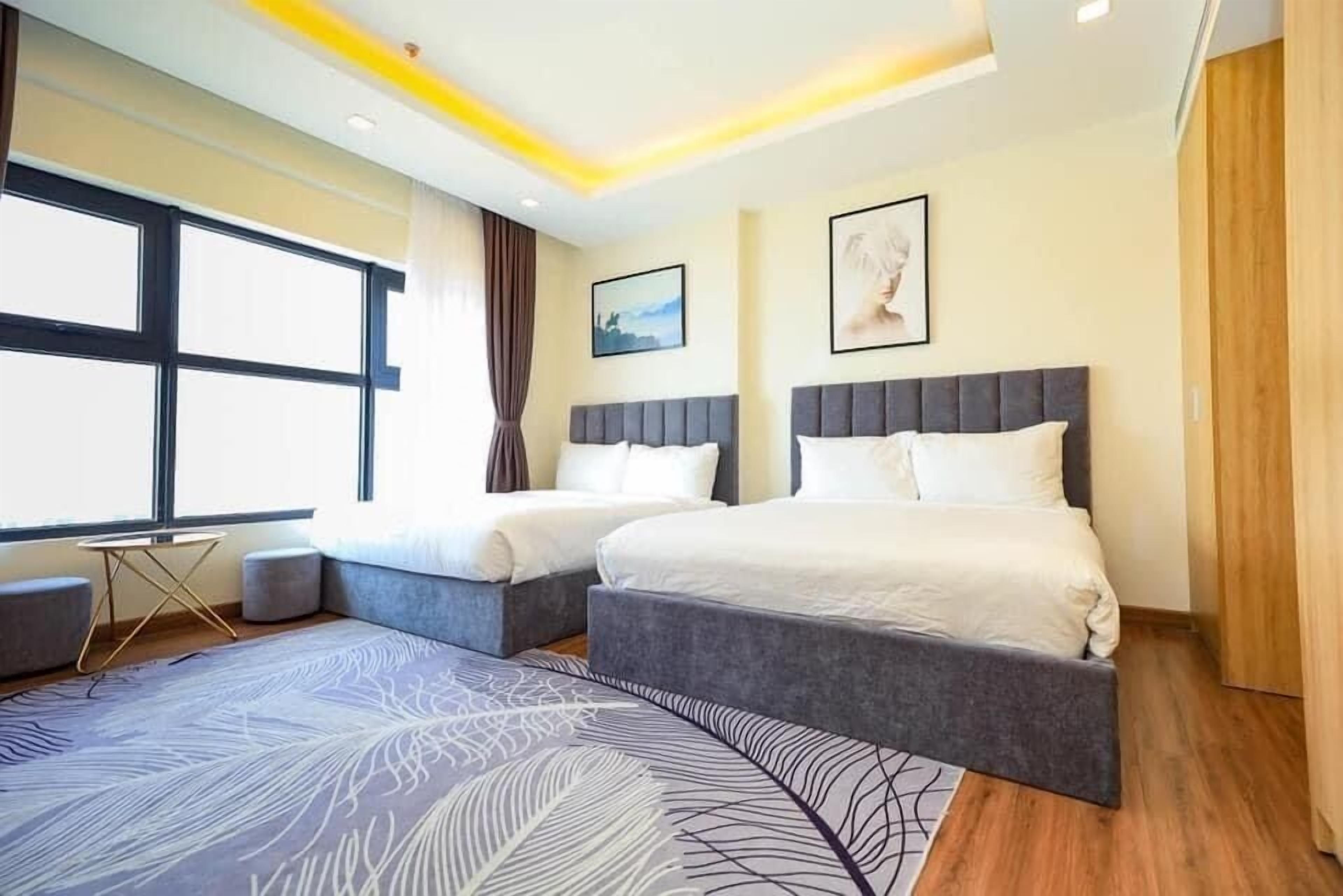 Une chambre d’hôtel moderne avec deux lits, une grande fenêtre et un tapis décoratif.