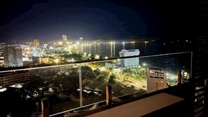 Panorama nocturn de la ciutat amb vistes al passeig marítim, edificis il·luminats i un cel clar.