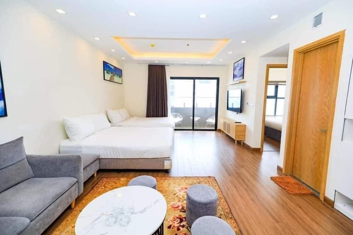 Una habitación de hotel moderna con una cama grande, un sofá, una mesa de centro y vistas al exterior.