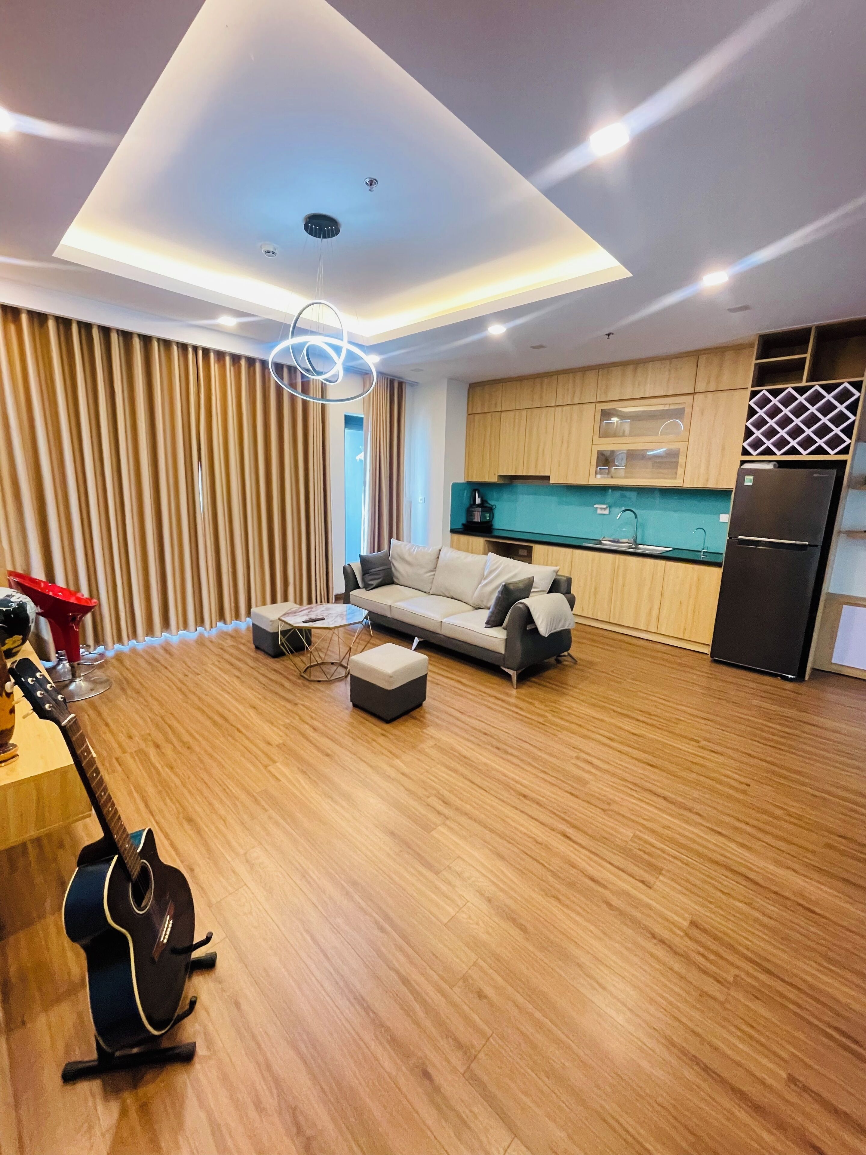 Een moderne woonkamer met een bank, een poef en een gitaar.
