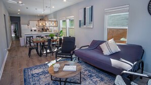 A modern living room with a sofa, coffee table, and dining area. - Spectacular Brand New 4br/2.5ba Near DT/ Riverwalk (San Antonio)