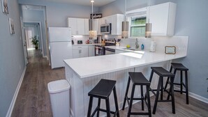A modern kitchen with white cabinets, a large island with bar stools, a microwave, and a sink. - Spectacular Brand New 4br/2.5ba Near DT/ Riverwalk (San Antonio)