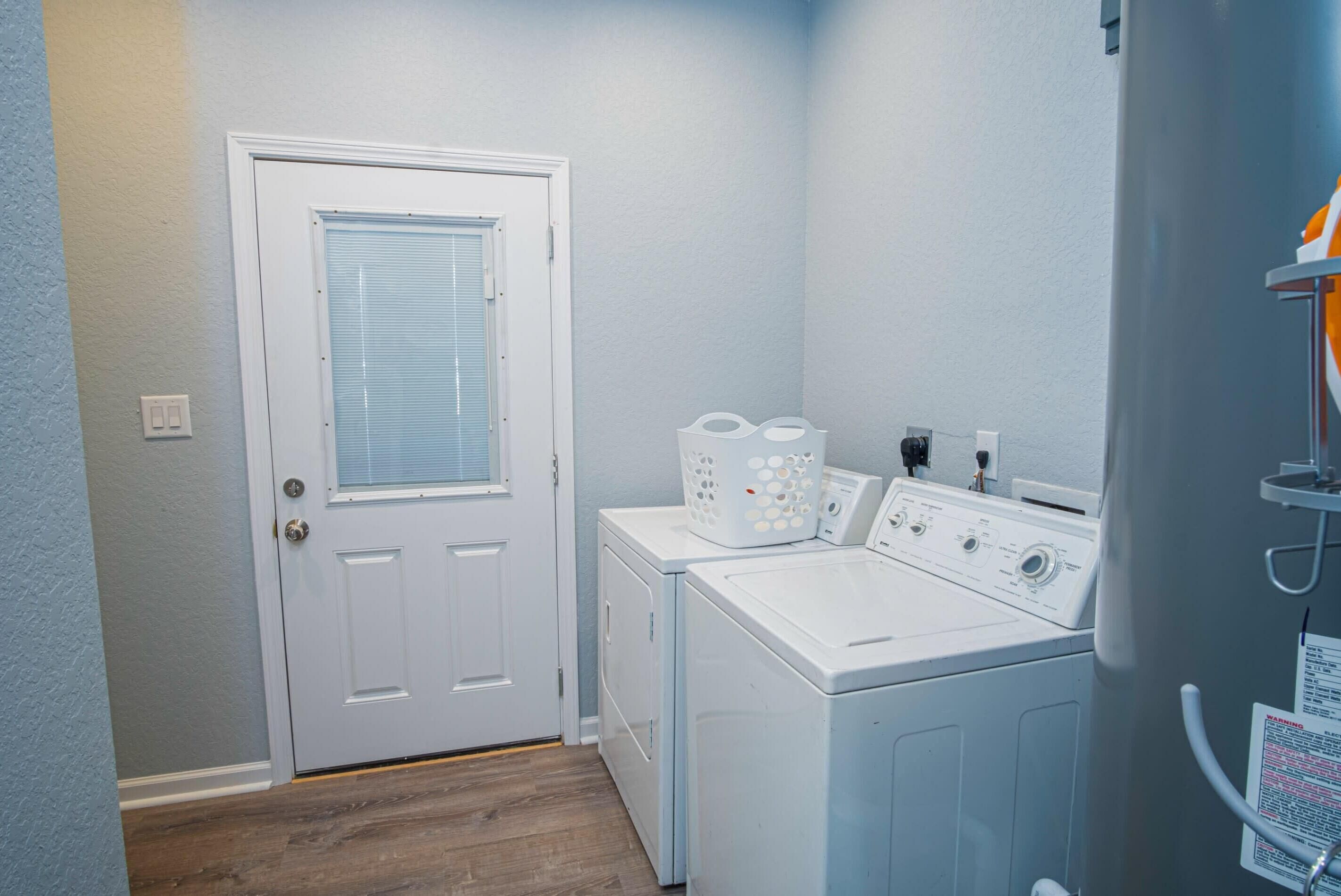 A laundry room with a door, a washer, a dryer, and a utility area with a water heater.