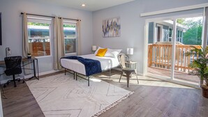 A bedroom with a bed, a desk, a chair, a ceiling fan, and a large window with a view of the outdoors. - Spectacular Brand New 4br/2.5ba Near DT/ Riverwalk (San Antonio)