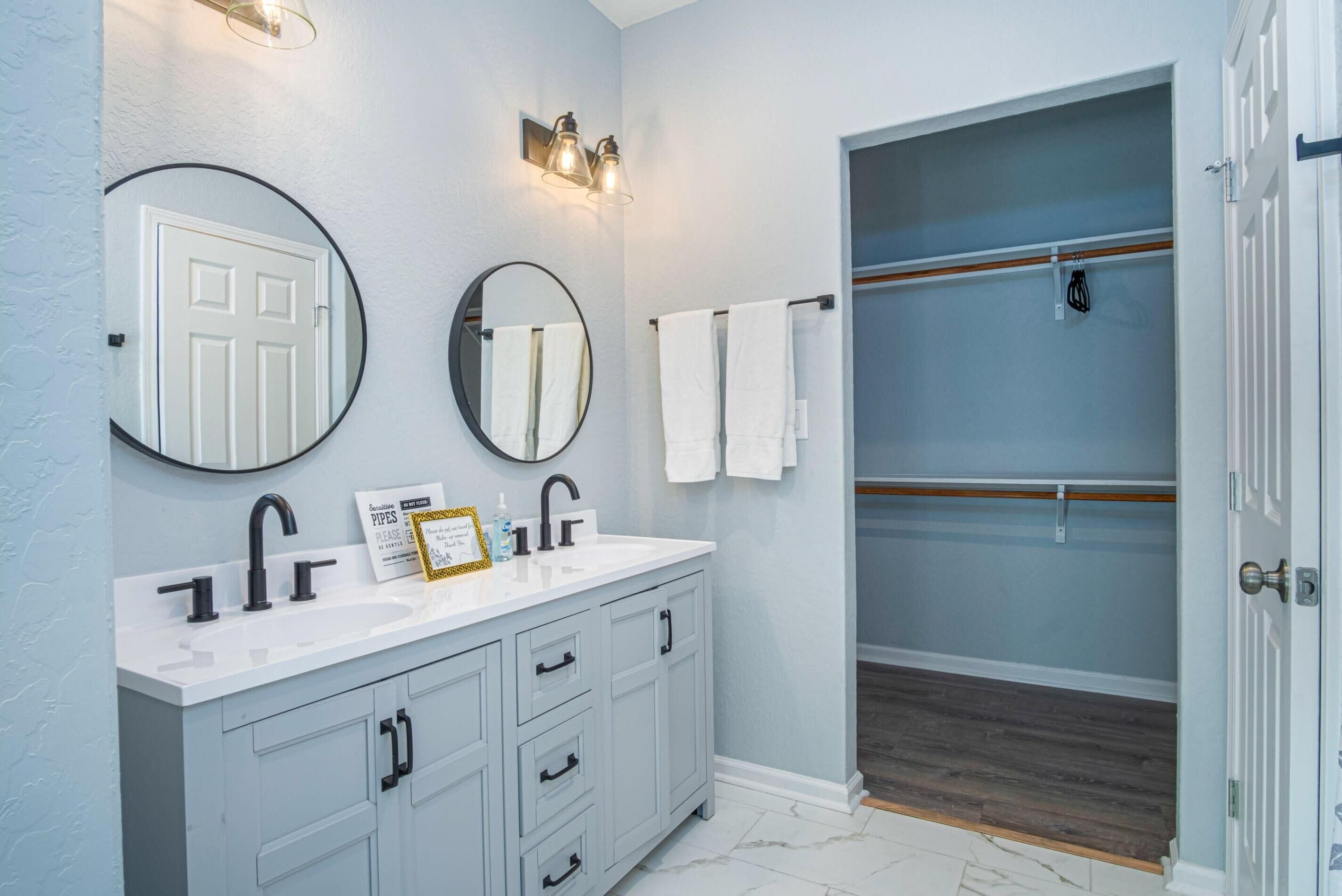 A bathroom with a white vanity, two mirrors, a towel rack, and a shower area.