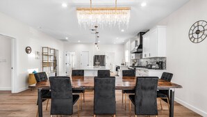 Una cocina moderna con armarios blancos, encimera negra y un reloj decorativo en la pared.