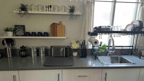 Una cocina moderna con armarios blancos, un tostador, un lavamanos y un escurreplatos.
