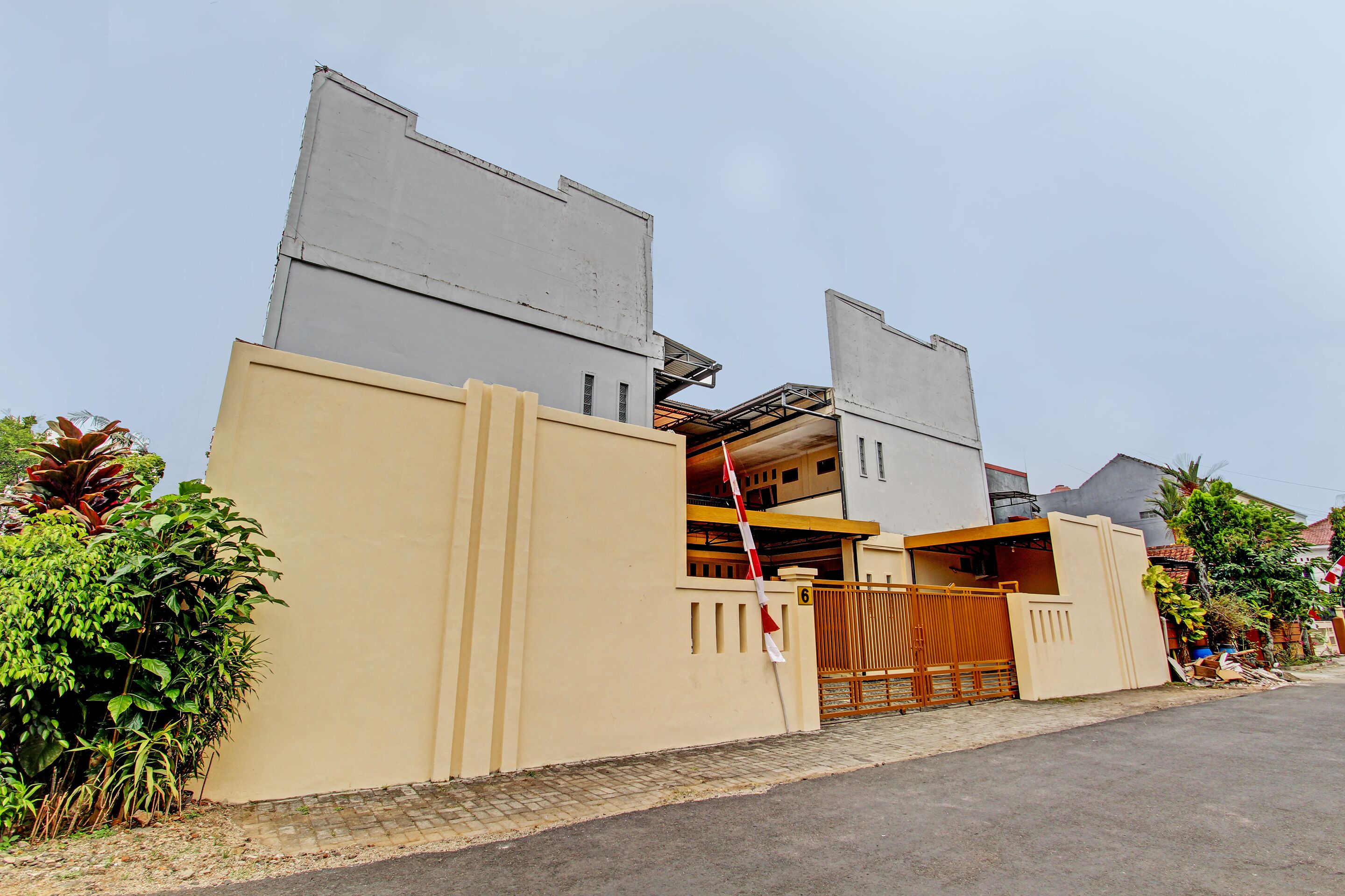A residential building with a gated entrance, a visible garage, and a number '6' on the gate.