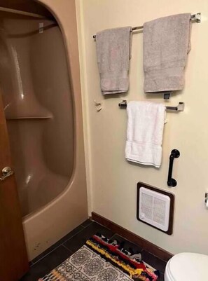 A bathroom with a bathtub, two towels on a rack, a toilet, and a patterned rug on the floor. - SnowMonte in the Pines

 (Dunmore)