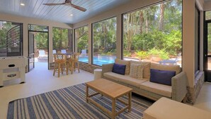 A modern living room with a sofa, coffee table, and a dining area with chairs.