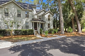 A two-story house with a front porch, a driveway, and surrounding trees.