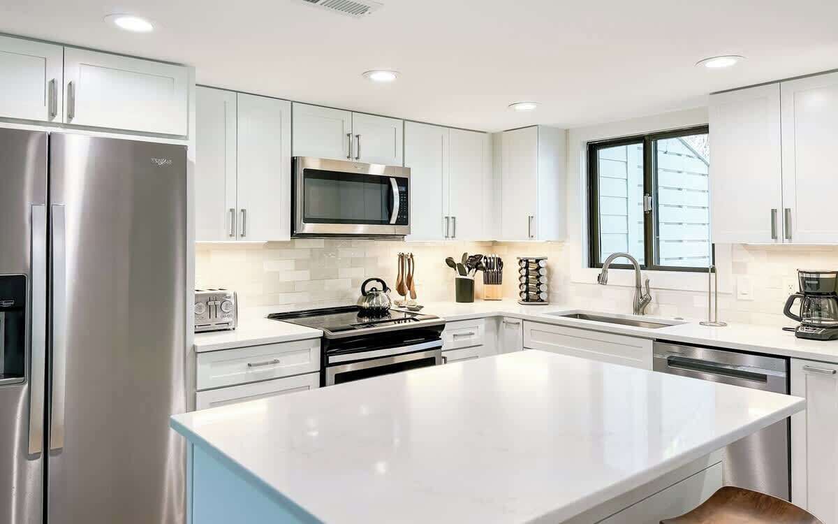 A modern kitchen with stainless steel appliances, white cabinetry, and a large island.