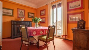 Une salle à manger avec une table ronde, des chaises et des œuvres d’art encadrées accrochées aux murs.