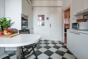 Keittiössä on ruutukuviollinen lattia, valkoinen pöytä ja mikroaaltouuni.