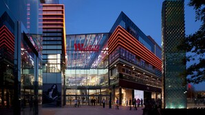 A modern building with a prominent casino sign, large glass windows, and a pedestrian area in front. - The Railway Tavern Hotel (London)