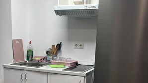 A modern kitchen with white cabinets, a stainless steel refrigerator, a built-in oven, and a ventilation hood. - Optimus Comfort Fusta 9 (Valencia)