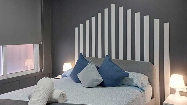A modern bedroom with a bed, pillows, a bedside table, and a window. - Optimus Comfort Fusta 9 (Valencia)